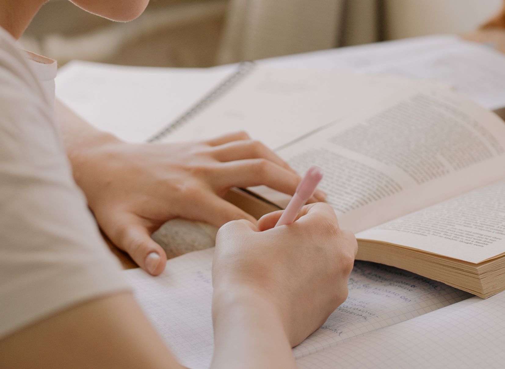 hands taking notes from reading into notebook.